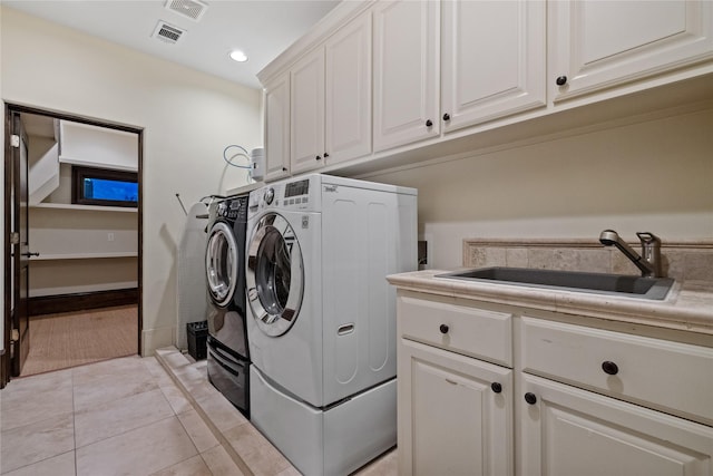 clothes washing area featuring visible vents, washer and clothes dryer, light tile patterned flooring, cabinet space, and a sink