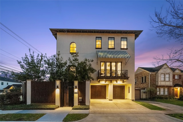 view of front of house with a garage, stucco siding, concrete driveway, and a balcony