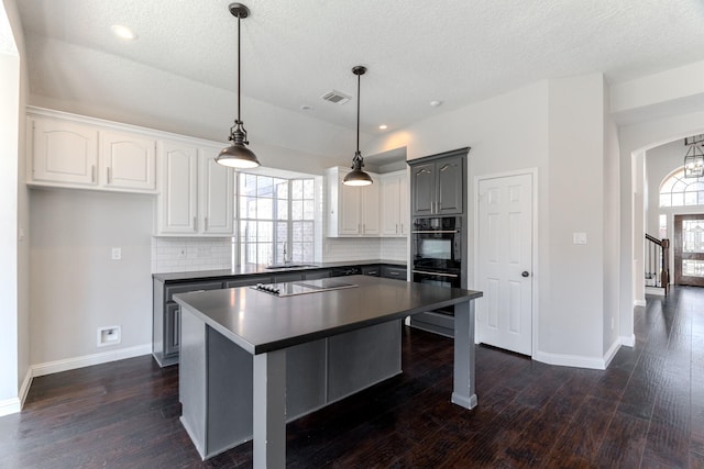 kitchen featuring a sink, decorative backsplash, dark countertops, and dark wood-style flooring