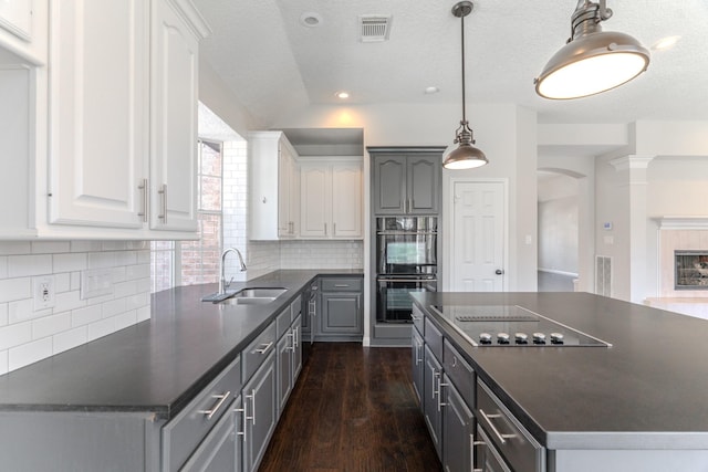 kitchen with a sink, visible vents, dark countertops, and black appliances