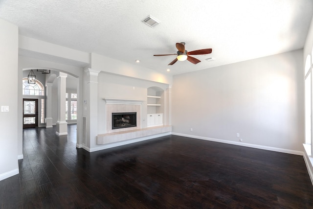 unfurnished living room with built in features, a ceiling fan, visible vents, ornate columns, and baseboards