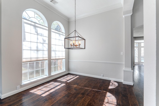 unfurnished dining area featuring visible vents, crown molding, baseboards, decorative columns, and wood-type flooring