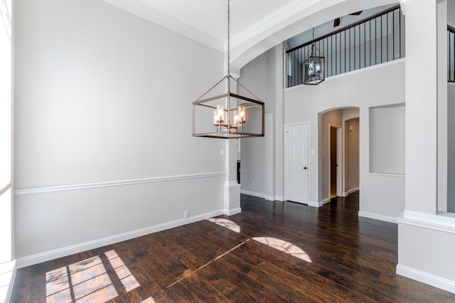 unfurnished dining area featuring a chandelier, arched walkways, crown molding, and hardwood / wood-style flooring