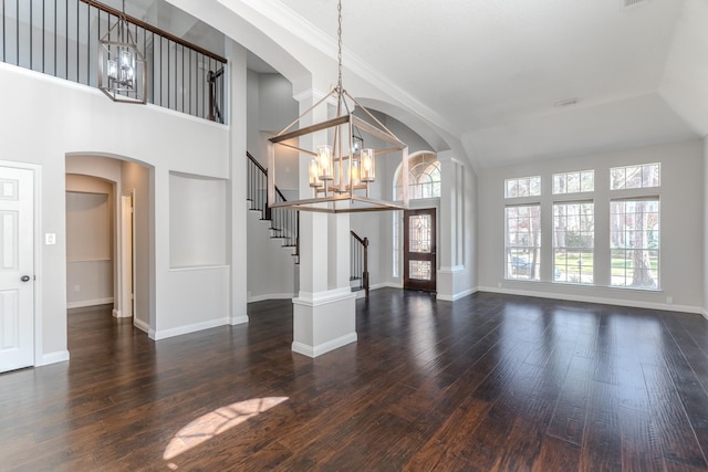 interior space featuring dark wood-type flooring, baseboards, stairs, an inviting chandelier, and arched walkways