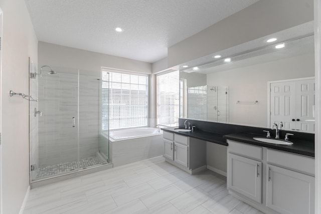 full bathroom with double vanity, a shower stall, a garden tub, and a sink