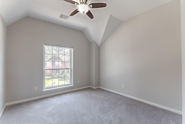 carpeted empty room with lofted ceiling, baseboards, visible vents, and ceiling fan