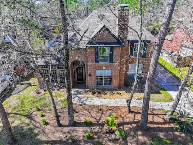 view of front of home with brick siding and roof with shingles