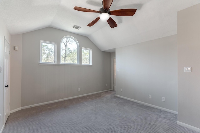 carpeted empty room with visible vents, baseboards, lofted ceiling, and ceiling fan