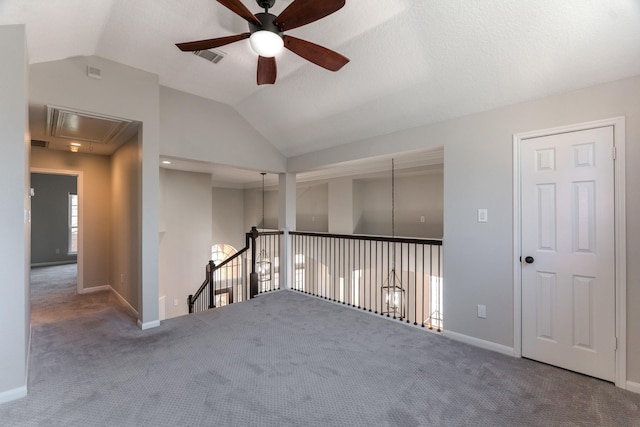 unfurnished room featuring baseboards, ceiling fan, carpet, attic access, and lofted ceiling