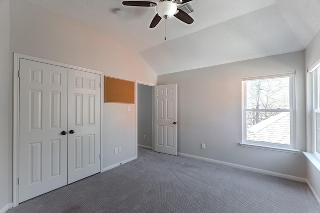 unfurnished bedroom with baseboards, lofted ceiling, a closet, a textured ceiling, and carpet flooring