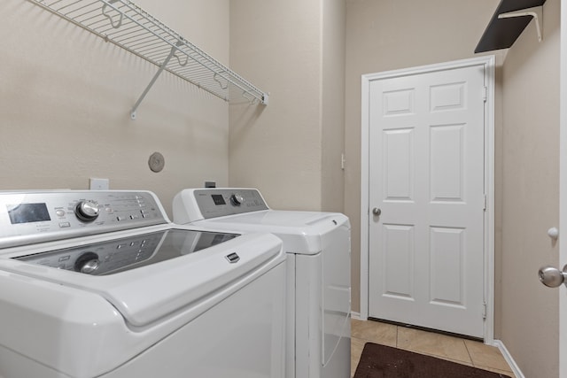 washroom with light tile patterned floors, laundry area, separate washer and dryer, and baseboards