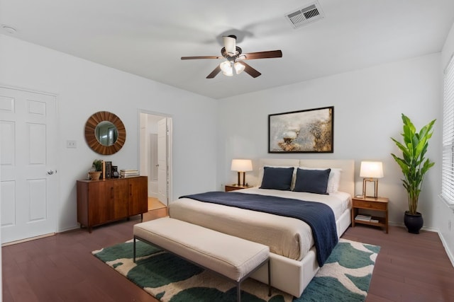 bedroom featuring baseboards, wood finished floors, visible vents, and connected bathroom