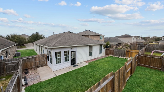 rear view of house with a shingled roof, a patio area, a lawn, and a fenced backyard