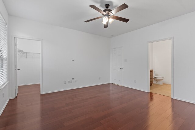 unfurnished bedroom with ceiling fan, connected bathroom, dark wood-type flooring, a spacious closet, and a closet