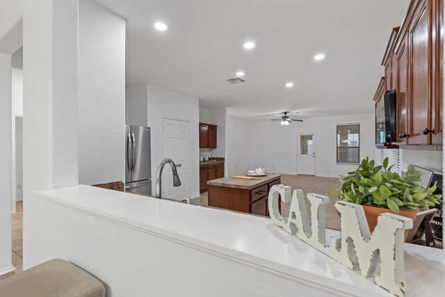 kitchen featuring recessed lighting, visible vents, freestanding refrigerator, a kitchen island, and a sink