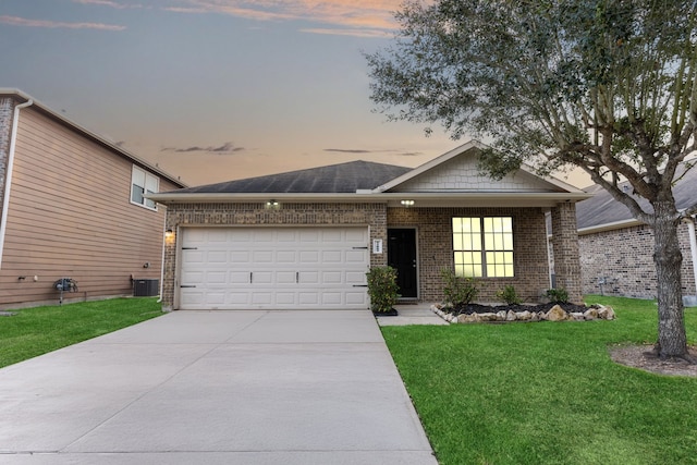 view of front of property with brick siding, an attached garage, central AC unit, a front yard, and driveway