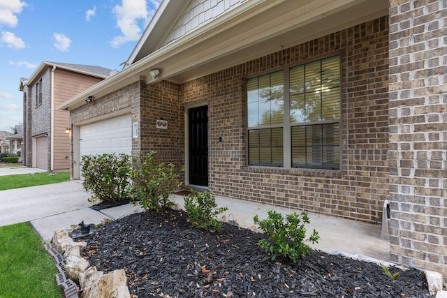 property entrance featuring a garage, concrete driveway, and brick siding