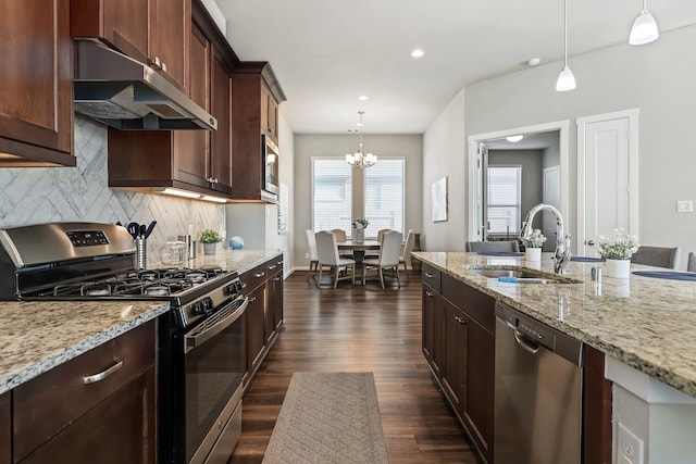 kitchen featuring dark wood finished floors, stainless steel appliances, tasteful backsplash, a sink, and under cabinet range hood