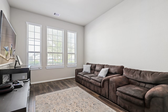 living area with baseboards, visible vents, and dark wood-type flooring
