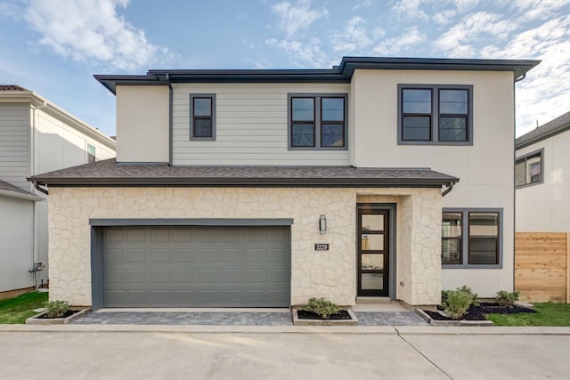 view of front of house featuring decorative driveway, roof with shingles, an attached garage, fence, and stone siding