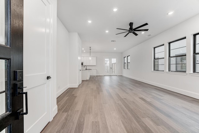 unfurnished living room with recessed lighting, visible vents, light wood-style floors, a sink, and baseboards