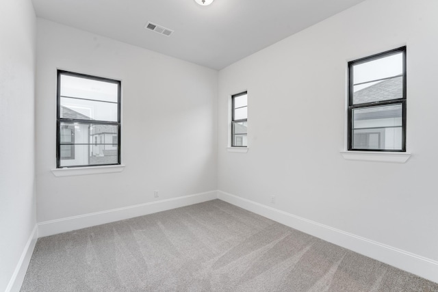 carpeted empty room featuring baseboards and visible vents