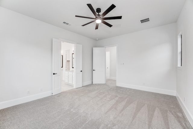 unfurnished bedroom featuring light carpet, ensuite bath, visible vents, and baseboards