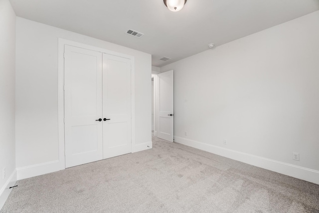 unfurnished bedroom with a closet, carpet flooring, visible vents, and baseboards