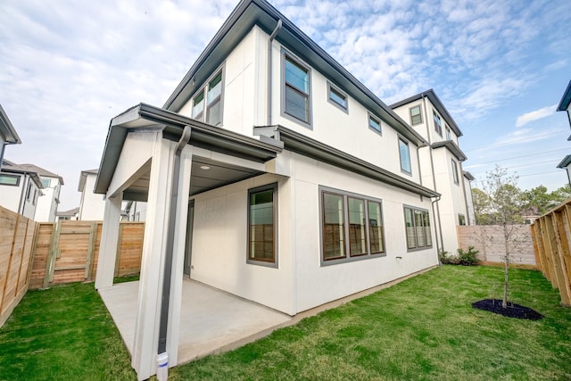 rear view of property featuring a patio, a lawn, a fenced backyard, and stucco siding