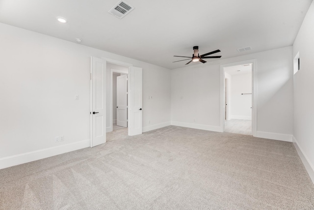 spare room featuring baseboards, ceiling fan, visible vents, and light colored carpet