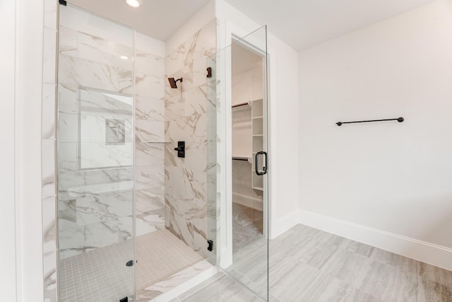 full bath featuring a marble finish shower, baseboards, a walk in closet, and recessed lighting