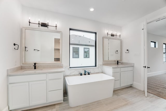 full bath with two vanities, a sink, and a healthy amount of sunlight