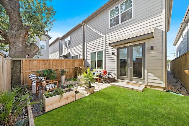 rear view of house with a garden, a lawn, and a fenced backyard