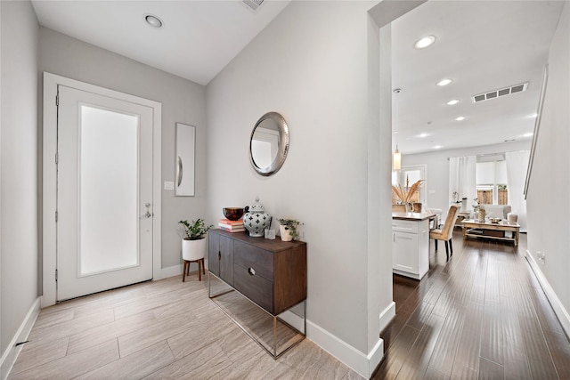 foyer featuring baseboards, visible vents, wood finished floors, and recessed lighting