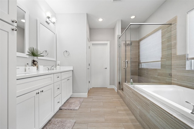 full bath with a garden tub, double vanity, recessed lighting, a shower stall, and baseboards