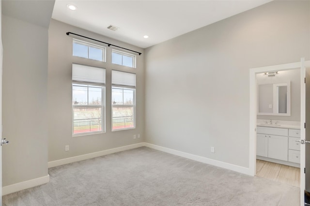 spare room featuring recessed lighting, light colored carpet, visible vents, a sink, and baseboards