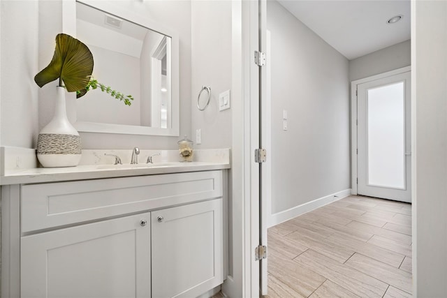 bathroom featuring wood finish floors, visible vents, vanity, and baseboards