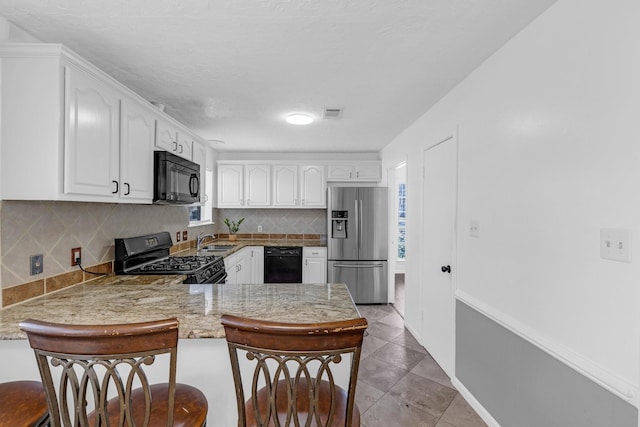 kitchen with white cabinets, a sink, a peninsula, and black appliances