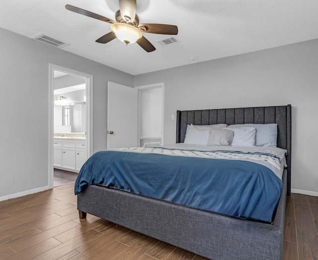 bedroom with visible vents, ensuite bathroom, ceiling fan, wood finished floors, and baseboards