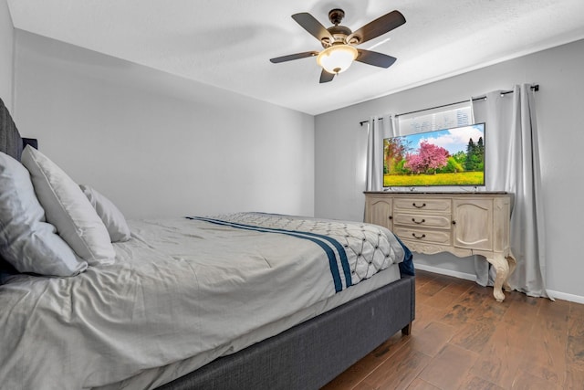 bedroom with dark wood-style floors, baseboards, and a ceiling fan