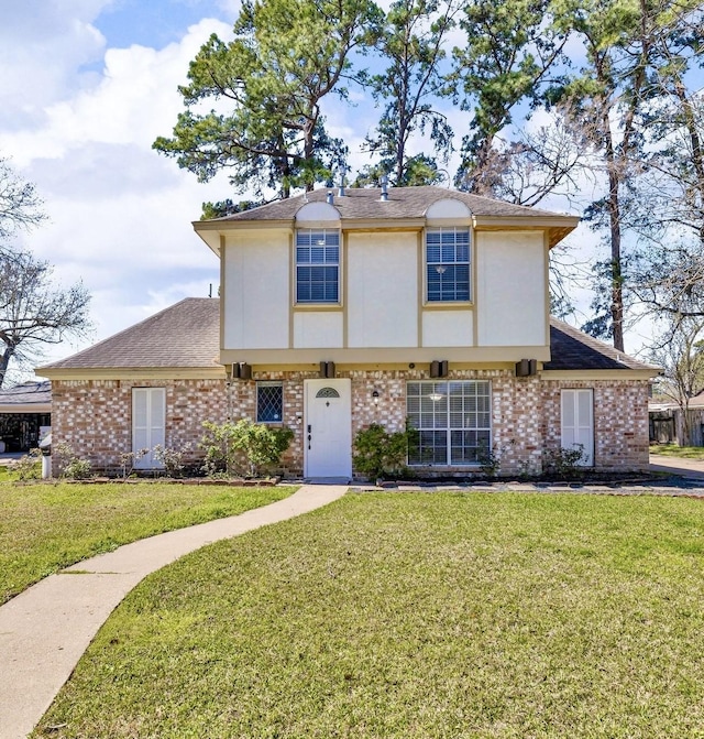 view of front of property featuring brick siding, stucco siding, and a front yard