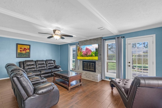 living room featuring wood finished floors, crown molding, a textured ceiling, a brick fireplace, and beam ceiling