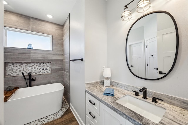 bathroom with vanity, a soaking tub, and wood finished floors