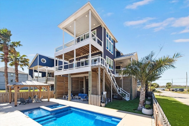 rear view of house with fence, stairway, metal roof, a patio area, and a standing seam roof