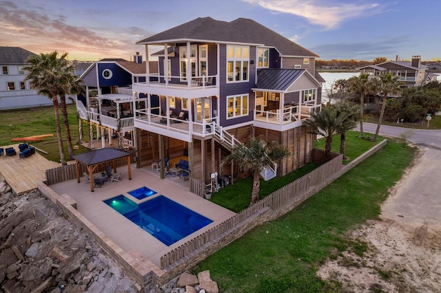 back of property featuring a standing seam roof, a patio area, fence, and driveway