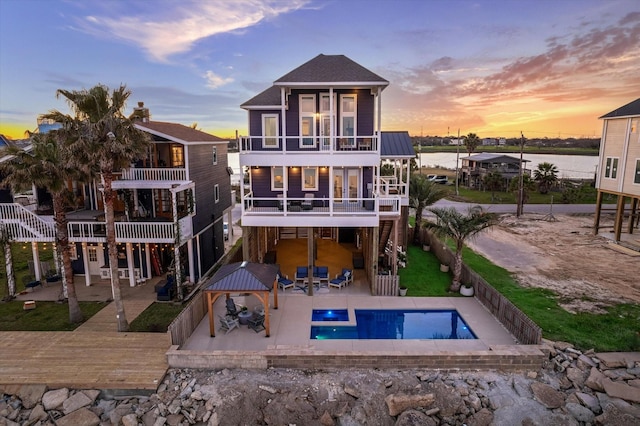 back of house featuring a balcony, a fenced backyard, an outdoor pool, a carport, and a patio area