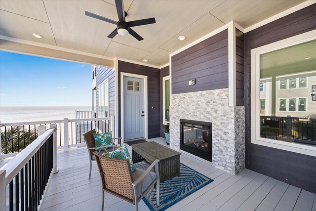 wooden terrace featuring a beach view, a ceiling fan, and a water view