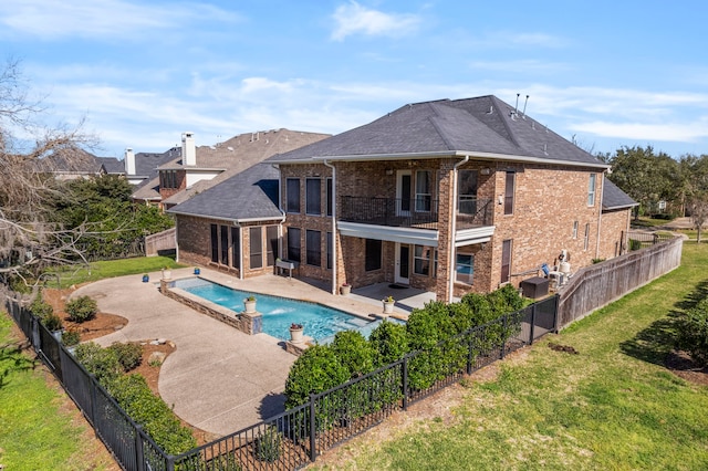 rear view of house with a balcony, a fenced backyard, a yard, a patio area, and brick siding