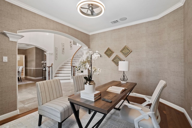 home office with arched walkways, crown molding, visible vents, wood finished floors, and wallpapered walls