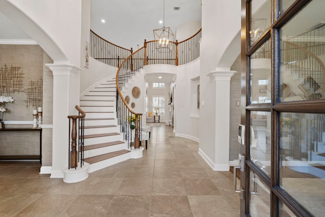 foyer with arched walkways, a chandelier, a high ceiling, stairs, and decorative columns